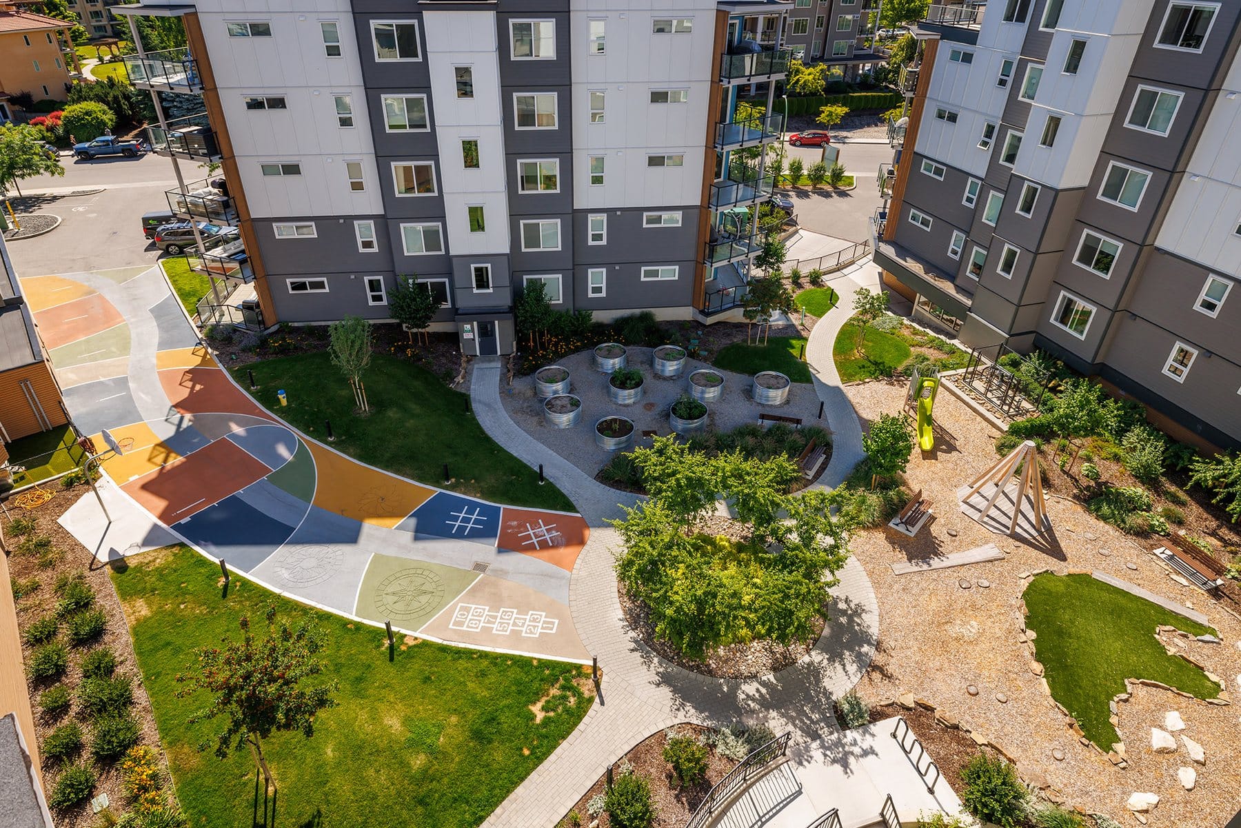The Green Square courtyard from above, with the painted sport court, garden plots and playground between the buildings