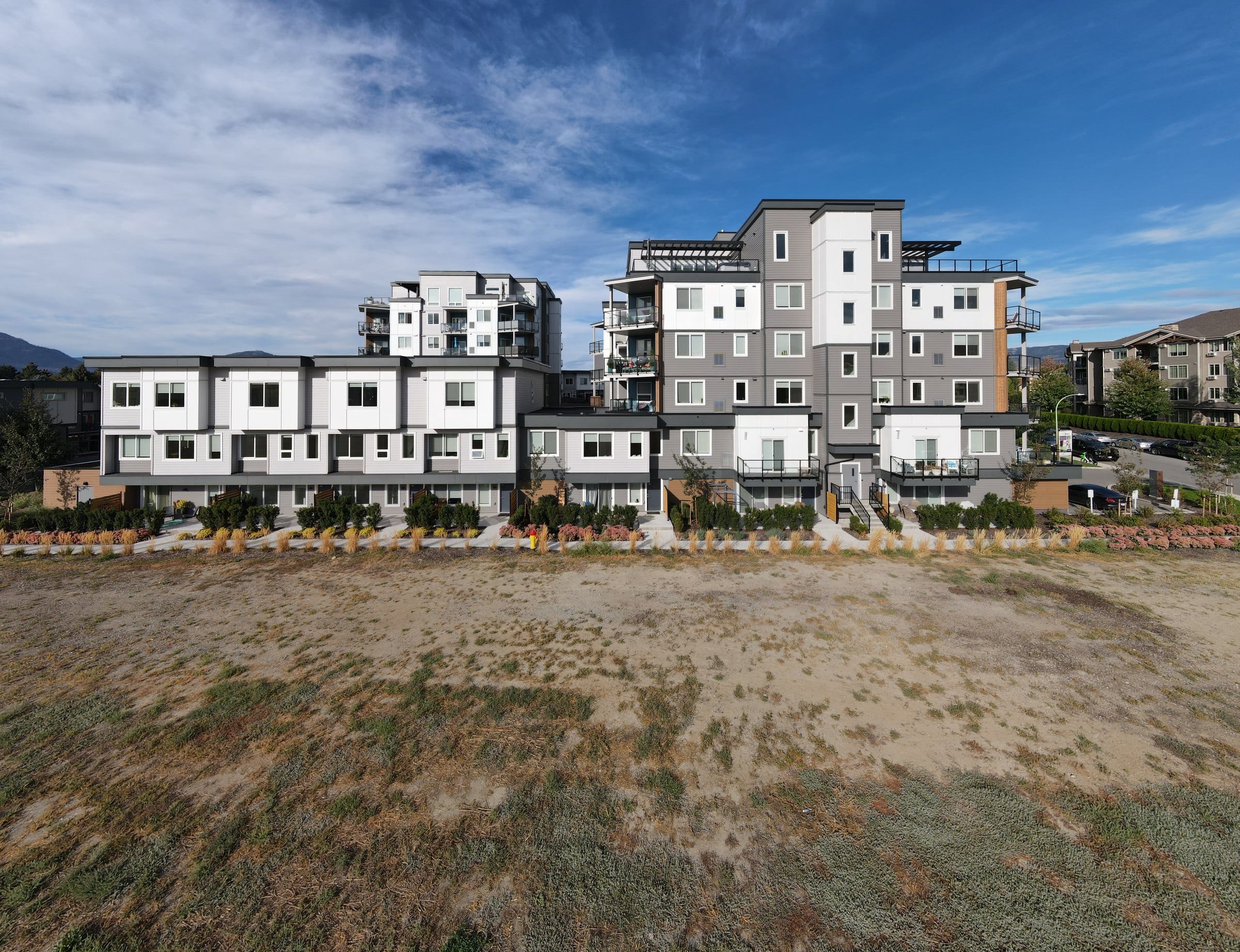 The townhome row and the 3634 tower at Green Square Vert in Kelowna, seen from the open field in front