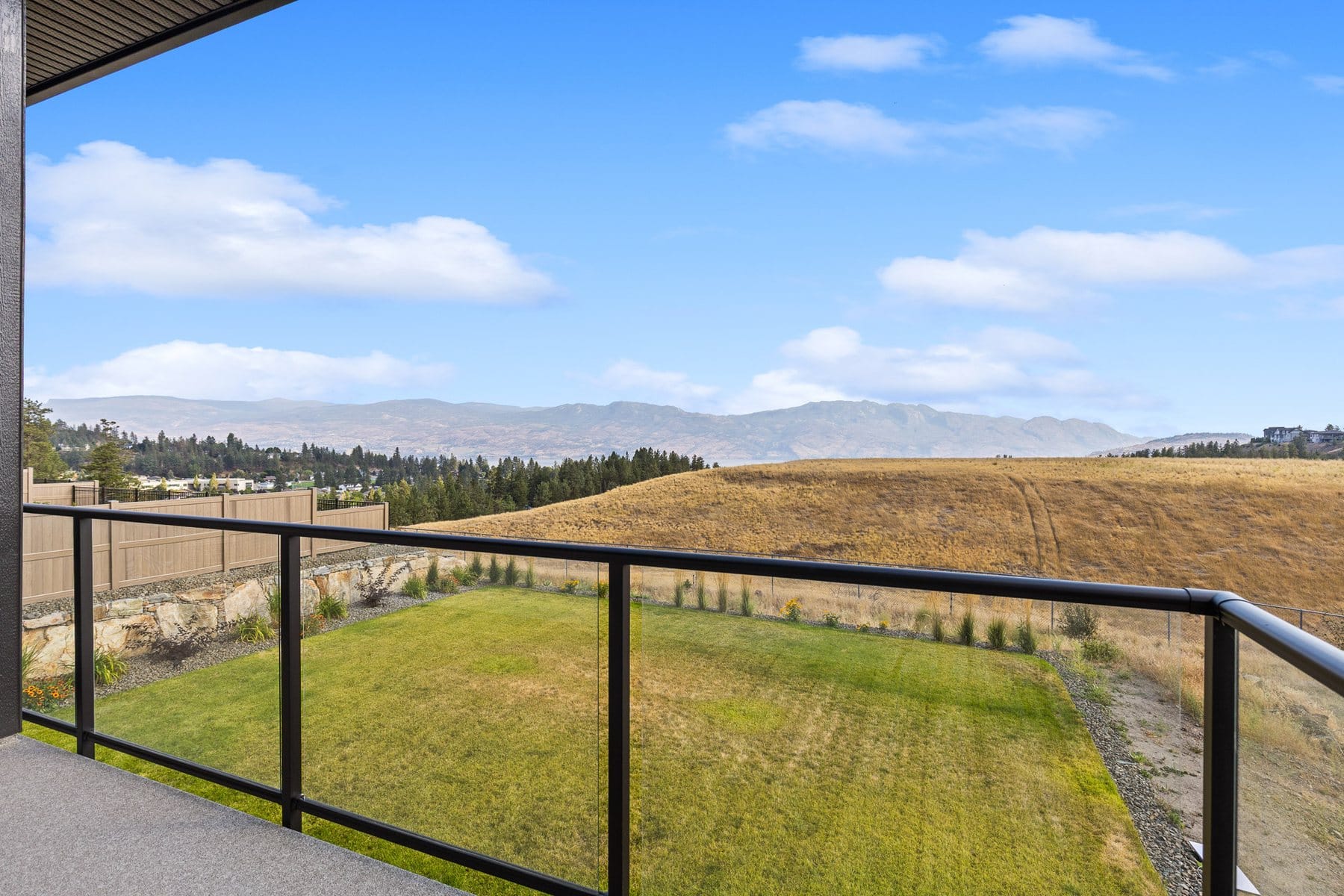 The flat backyard at 2531 Pinnacle Ridge Drive from the deck, open grassland and mountains beyond